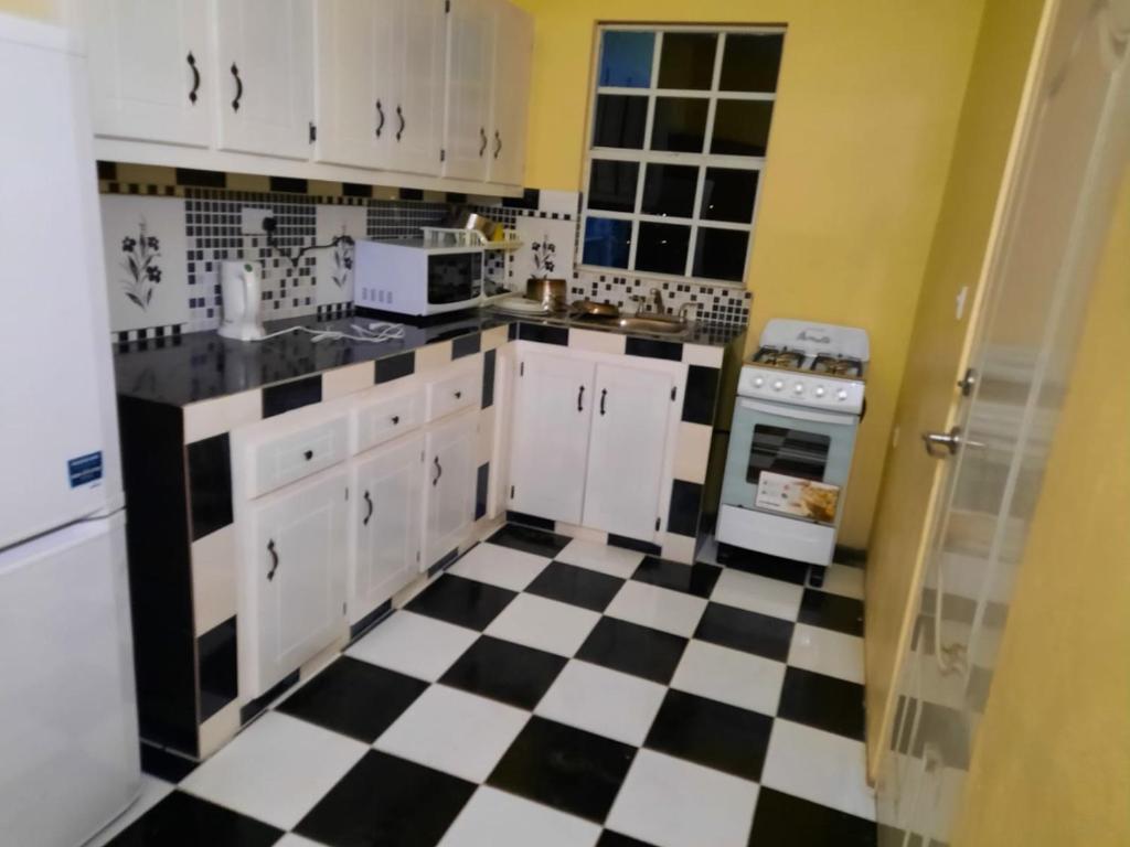 een keuken met een zwart-wit geruite vloer bij City View Accomodations Apt 2 in Roseau