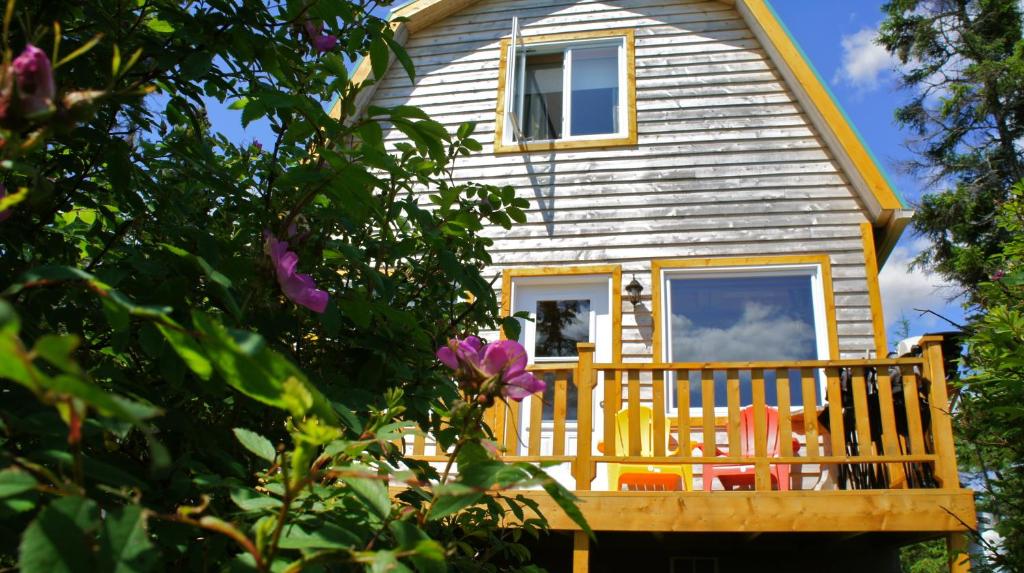 a house with a porch and flowers in front of it at Chalets du bout du monde in Gaspé