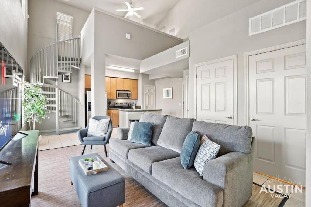 uma sala de estar com um sofá cinzento e uma cozinha em Balcony Skyline View Spiral Staircase Near UT em Austin