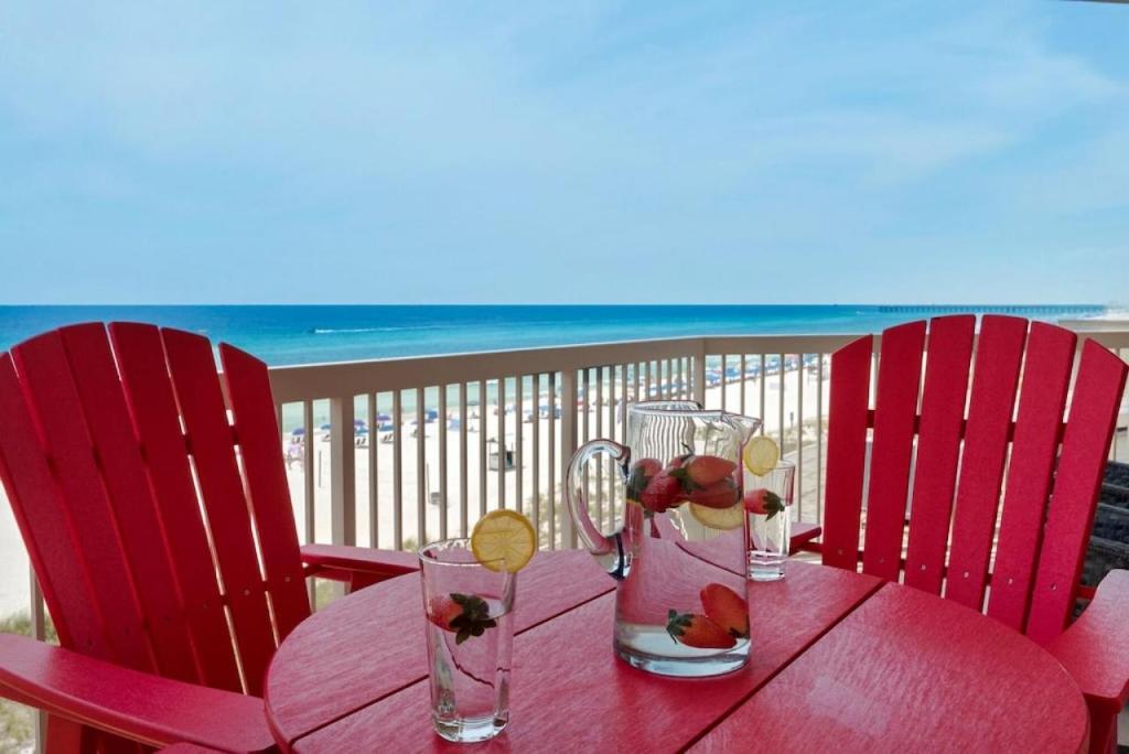 een rode tafel met twee stoelen en een tafel met twee glazen bij Sunrise Beach 511 in Panama City Beach