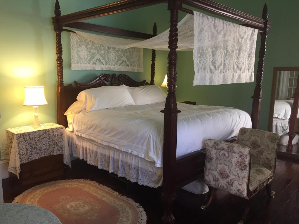 a bedroom with a four poster bed and two chairs at 1872 Denham Inn in Monticello