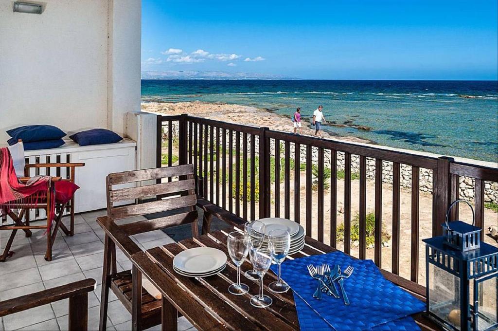 einen Tisch auf dem Balkon mit Blick auf den Strand in der Unterkunft Oltremare Marzamemi in Marzamemi