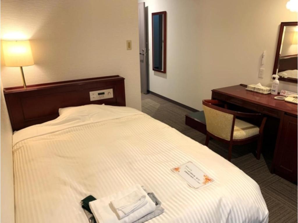 a hotel room with a bed with a desk and a mirror at Hitoyoshi Onsen Hotel Hananoshou - Vacation STAY 40074v in Hitoyoshi