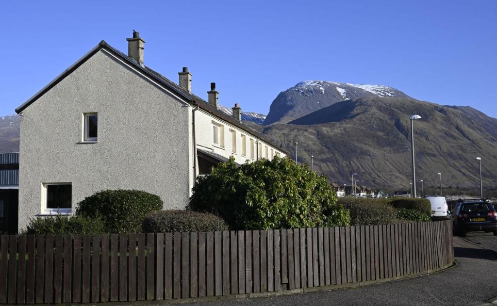 een huis met een hek voor een berg bij Sealladh Mairi in Fort William
