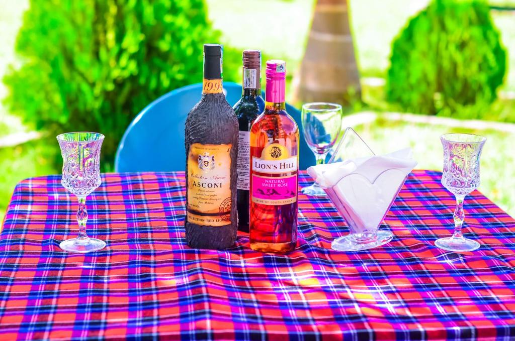 tres botellas de vino sentadas en una mesa con copas en Muhako Hotel en Dar es Salaam