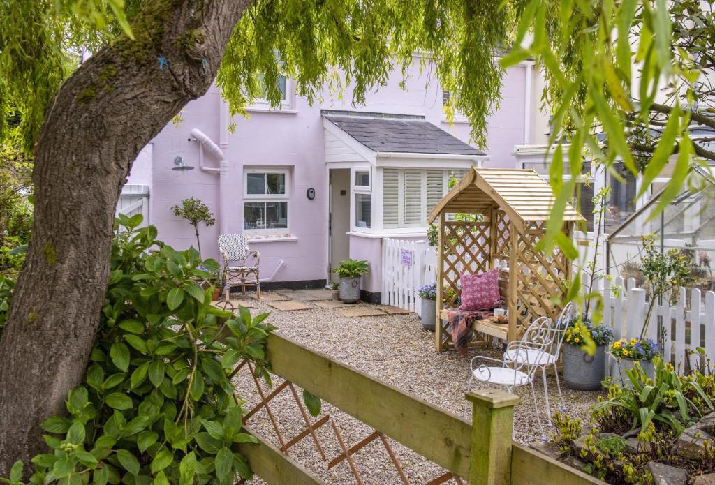 a pink house with a fence and a tree at Pink Cottage in Penzance
