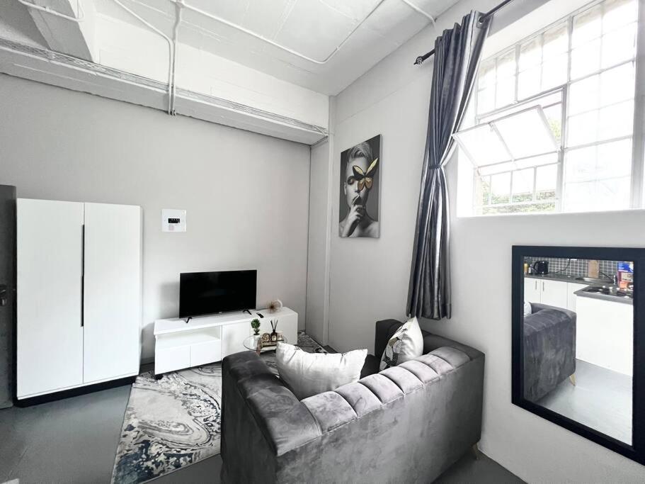 sala de estar con sofá y TV en Posh Apartment next to Maboneng, en Johannesburgo
