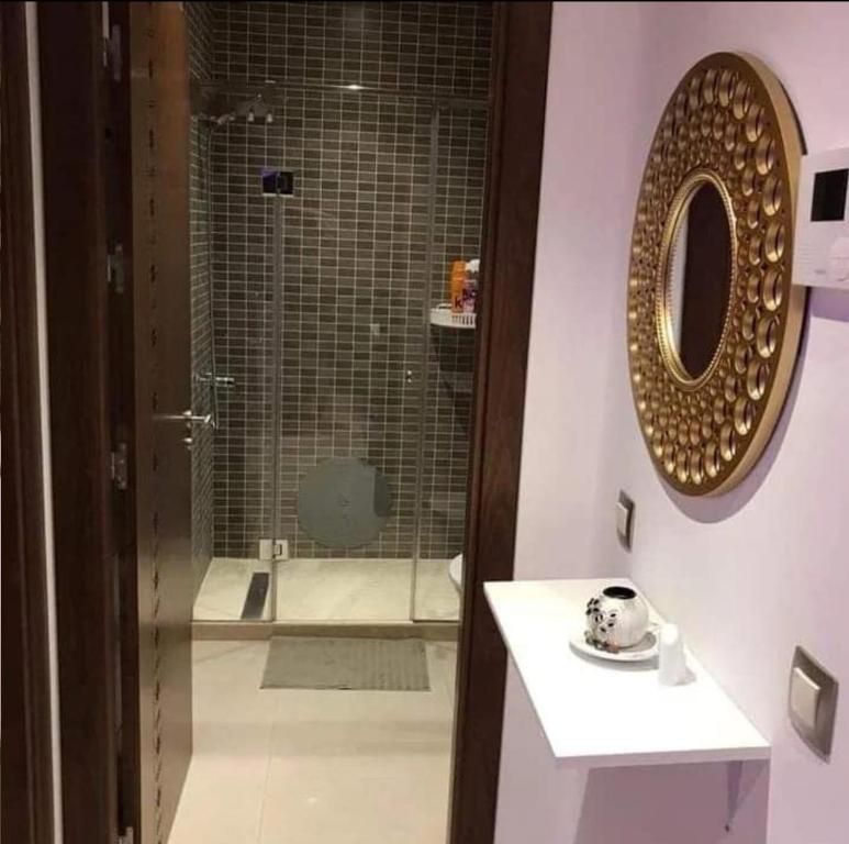 een badkamer met een douche, een wastafel en een spiegel bij Ain lbaida in Casablanca