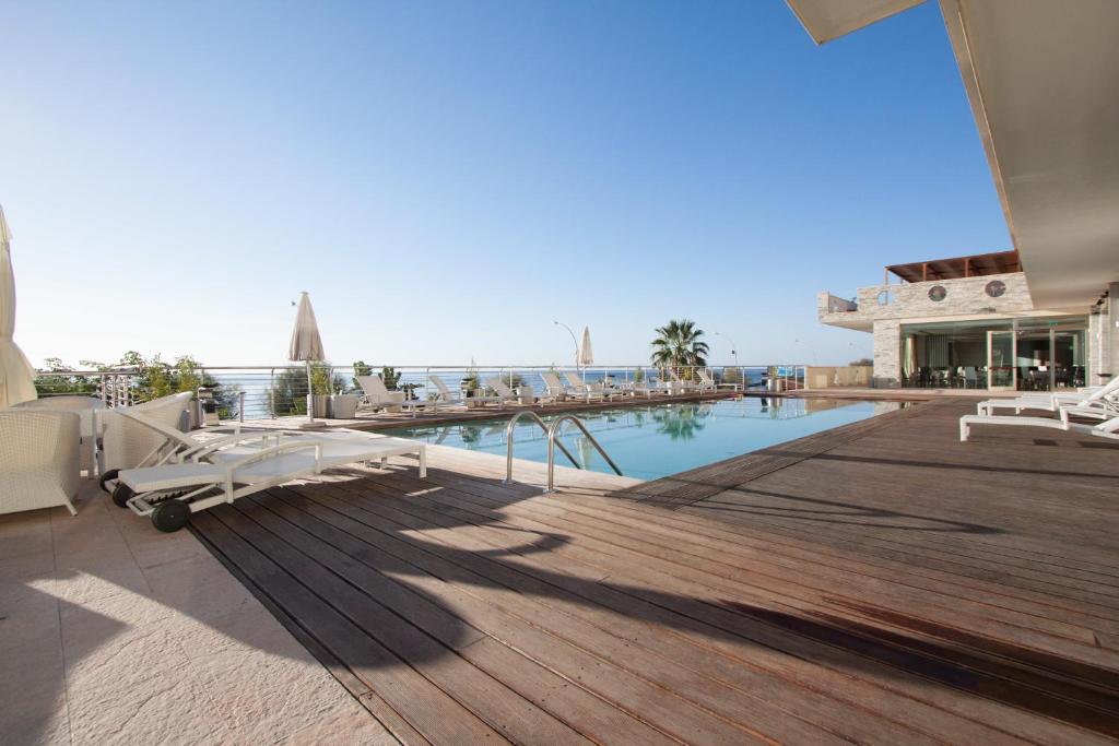 a resort with a pool and a deck with chairs at Main Palace Hotel in Roccalumera