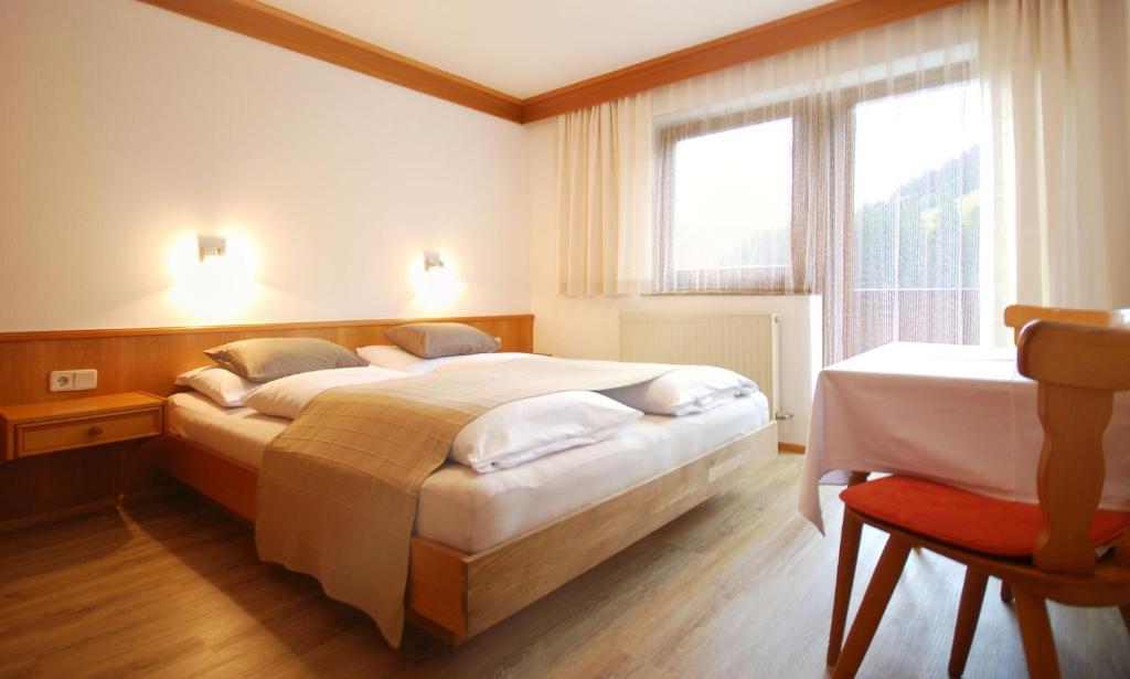 a hotel room with two beds and a chair at Appartementhaus Daniel in Saalbach-Hinterglemm