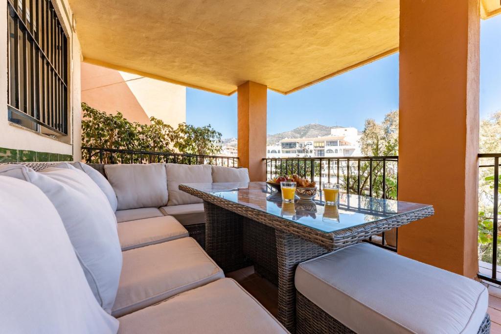 een patio met een tafel en stoelen op een balkon bij Seaside Bliss 2BR Apartment with Tranquil Terrace Pool and Parking in Fuengirola