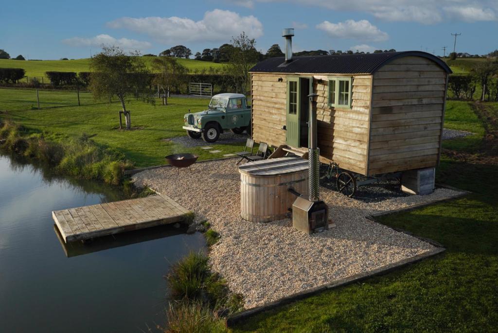 a tiny house next to a body of water at Four Acres Farm Shepherds Huts in Donaghadee