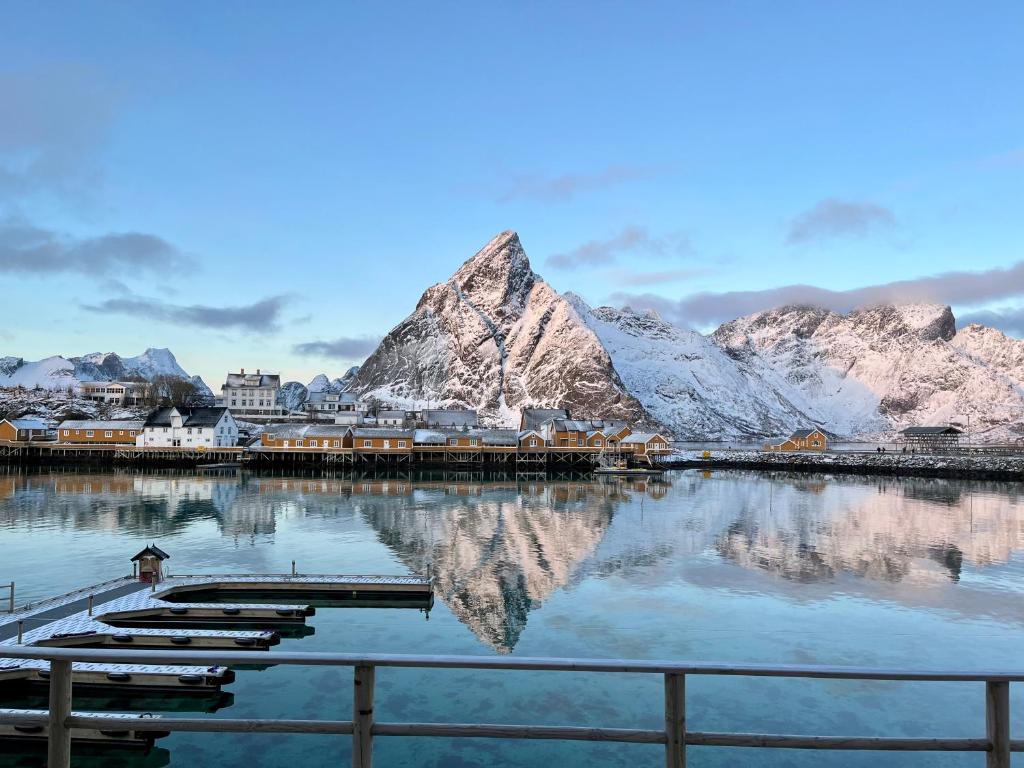 une réflexion de montagne dans une masse d'eau avec des bateaux dans l'établissement Rostad Retro Rorbuer, à Reine