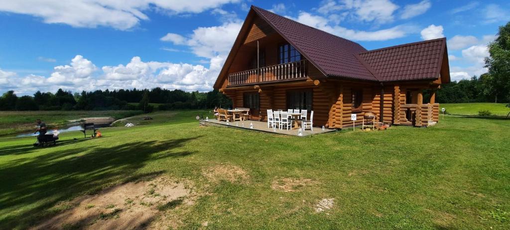 a log cabin on a grassy field with people standing outside at Meijas Nams in Kalupe