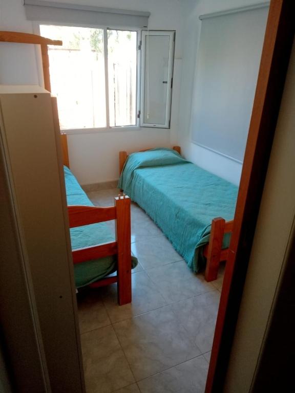a bedroom with two beds and a chair and a window at NUESTRO MUNDO TRELEW in Trelew