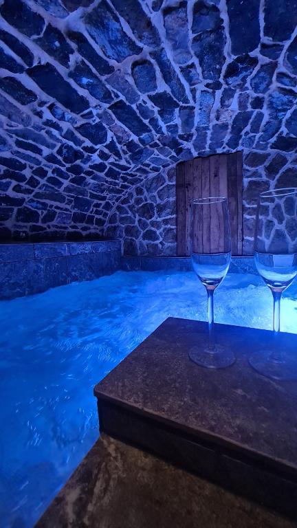 2 verres à vin assis sur une table à côté d'une piscine dans l'établissement Ô Nuit Claire, superbe longère avec spa., à Dompierre-sur-Helpe