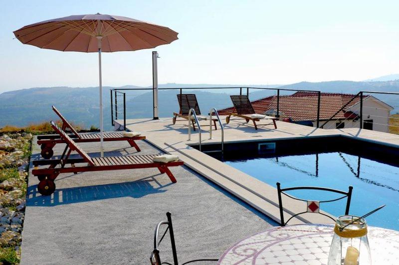 einen Pool mit 2 Stühlen und einem Sonnenschirm in der Unterkunft Villa Branko in Ravno