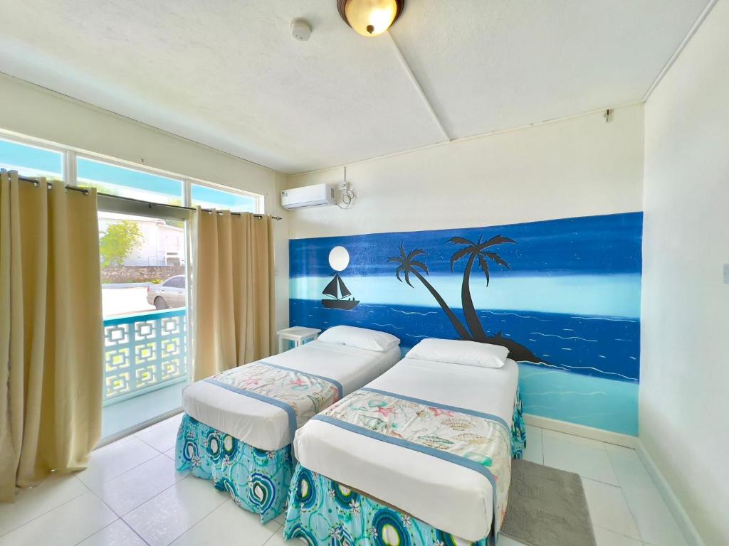 two beds in a room with a painting on the wall at Nautilus Ocean Suites in Bridgetown