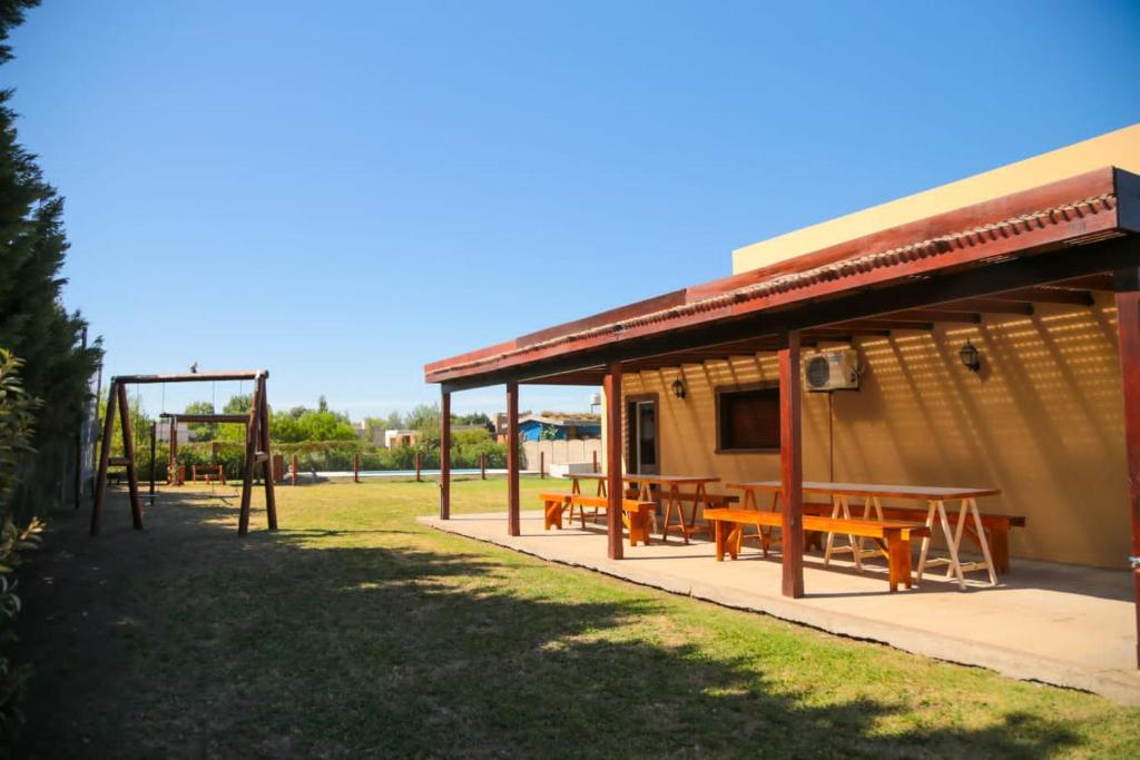 un refugio de picnic con mesas de picnic y un columpio en Quinta La Inocencia en Trenque Lauquen