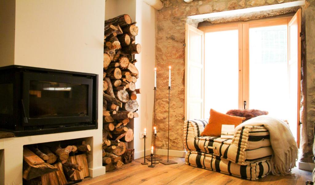 a living room with a fireplace with a tv and a chair at Clauhomes Casa Rural Deluxe in Tarrés