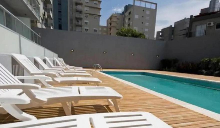 una fila de tumbonas blancas junto a una piscina en Hermoso Departamento en Palermo Hollywood y cerca de Movistar Arena en Buenos Aires
