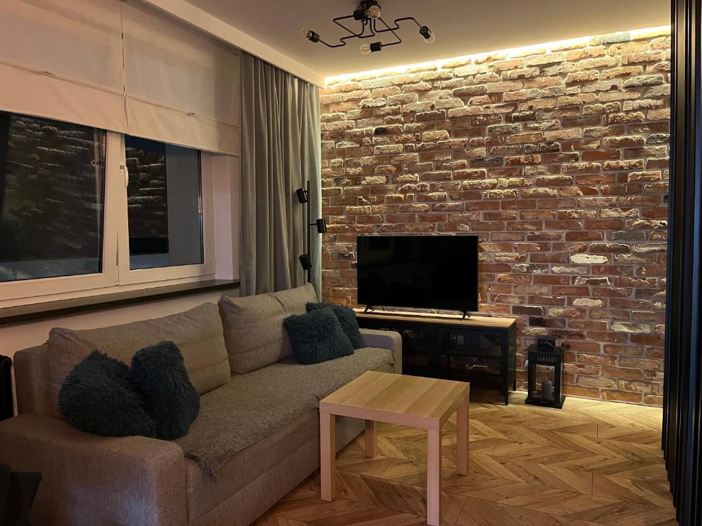a living room with a couch and a brick wall at Luksusowy loft nad jeziorem Swarzędz koło Poznań in Swarzędz