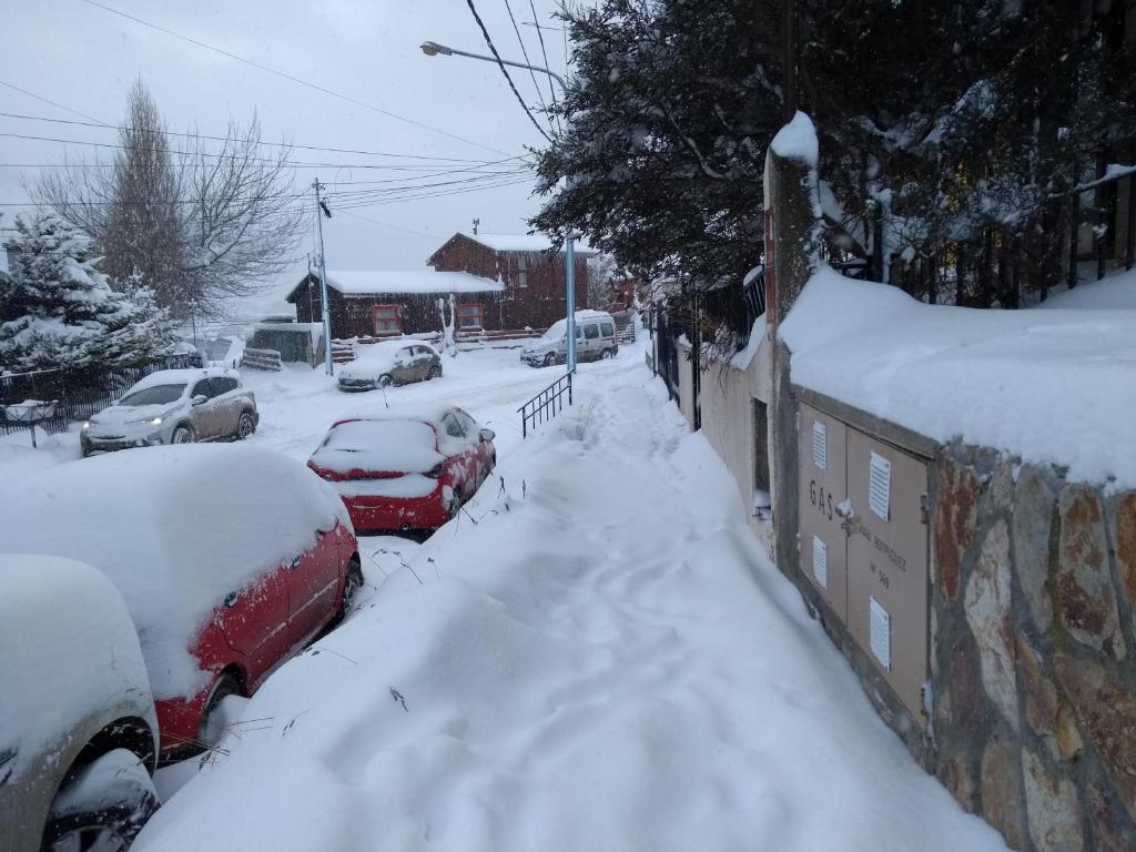 una strada ricoperta di neve con auto parcheggiate sopra di QONDADO a Ushuaia