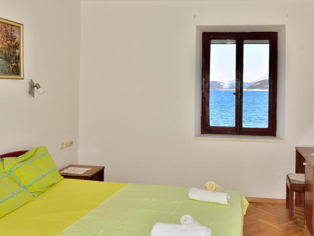 a bedroom with a green bed and a window at Dream Beloc House Lopud Island in Lopud