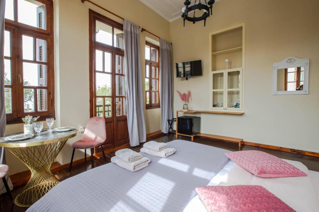 um quarto com uma cama, uma mesa e janelas em Ruby 'n Emerald studio's em Rethymno Town