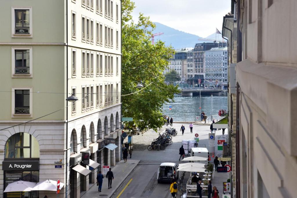Hôtel Rousseau Plus في جنيف: شارع المدينة فيه مباني والناس تمشي على الشارع