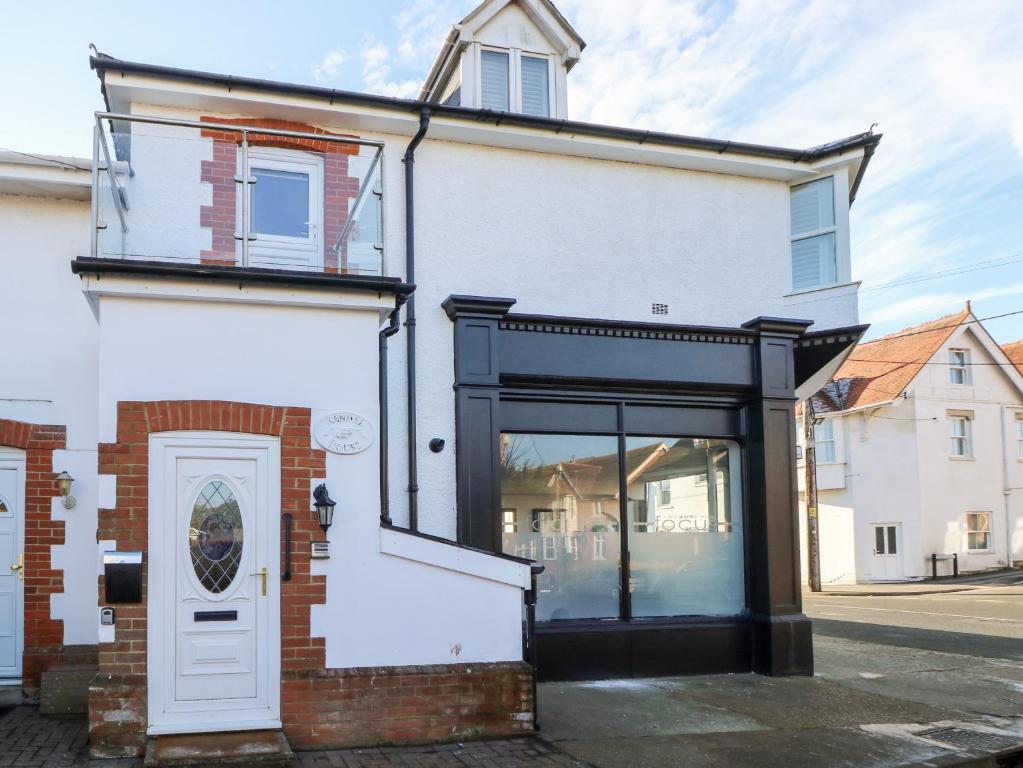 a white building with a door and a window at The Snug in Totland