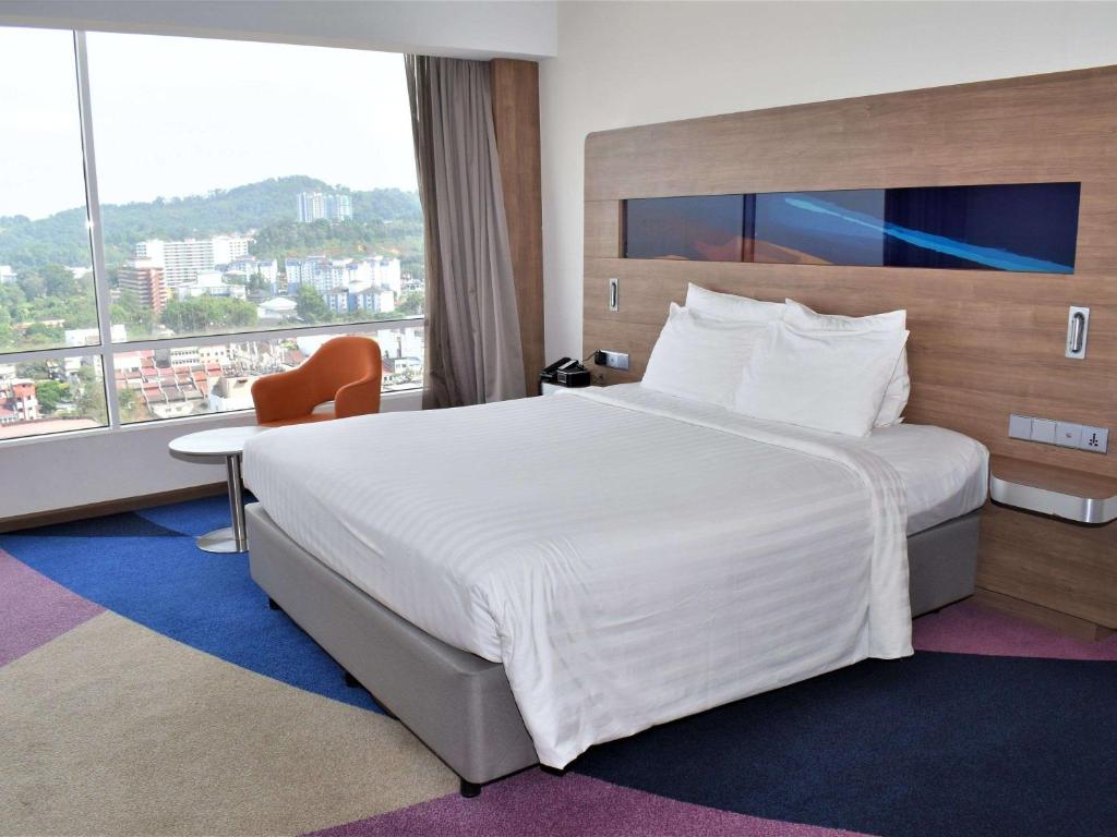 a hotel room with a large bed and a large window at Novotel Taiping in Taiping