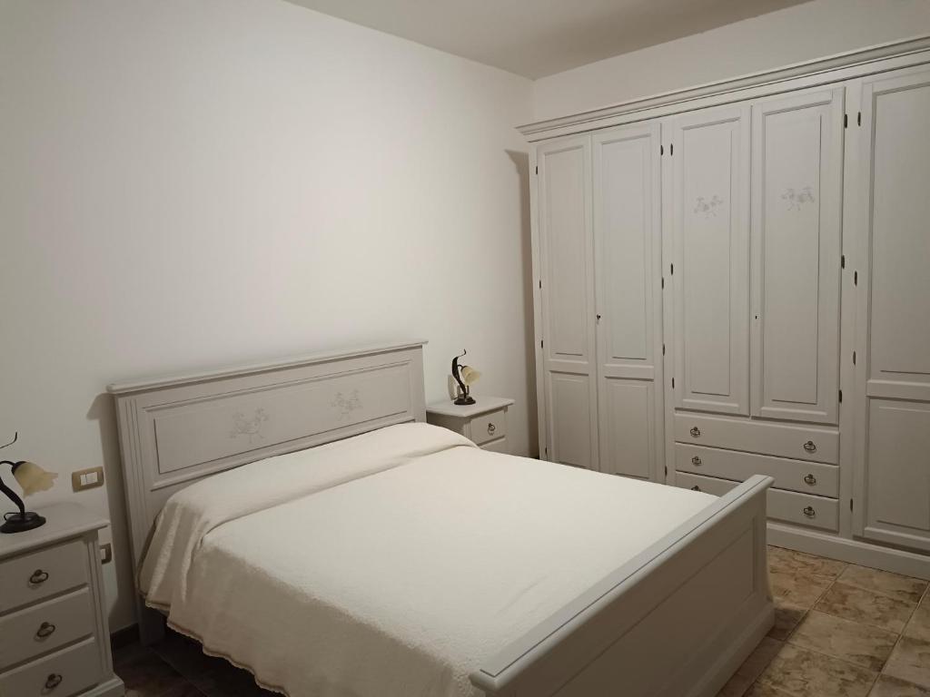 een witte slaapkamer met een wit bed en kasten bij CASA ZENOBIO in Pabillonis