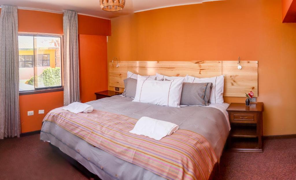 1 dormitorio con 1 cama grande y pared de color naranja en Colibrí Inn en Chivay