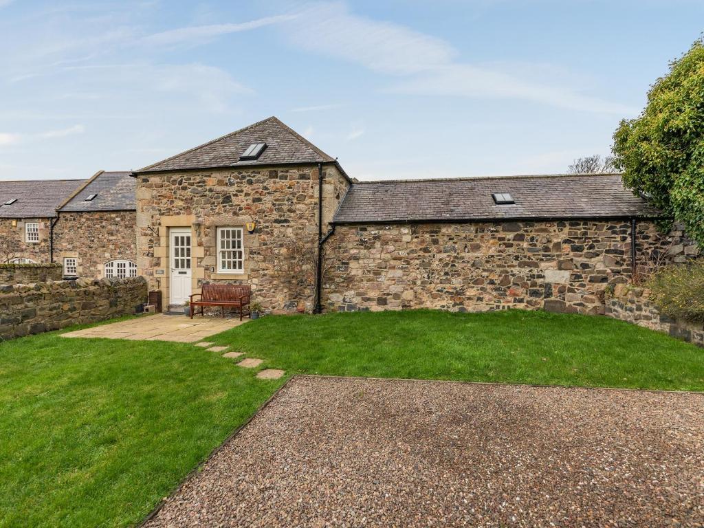 een uitzicht op een stenen huis met een tuin bij Puffin Cottage - Uk42131 in Bamburgh