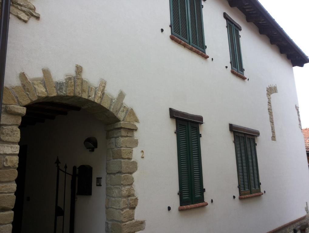 a white building with green shutters on it at Conte Caramelli Apartment in Montelupo Albese