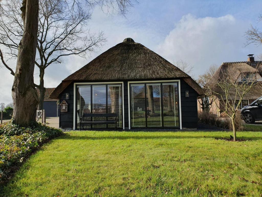 una casa con techo de paja y patio en Cozy holiday home in Overijssel in a wonderful environment, en De Meele