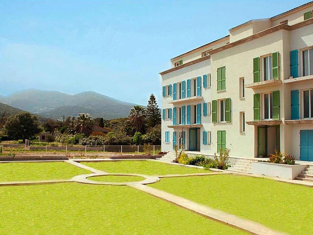 un grand bâtiment avec une cour en gazon devant lui dans l'établissement Apartment in Macinaggio by the Marina, à Rogliano
