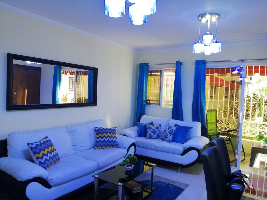 uma sala de estar com sofás azuis e cortinas azuis em Hermoso y cómodo apartamento familiar en Ciudad Juan Bosch em Los Paredones