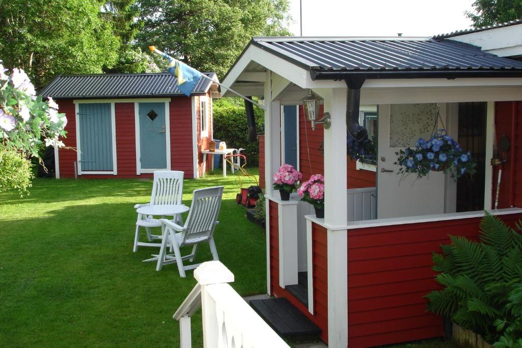 Cabaña roja con mesa y sillas en el césped en Karlholm Snatra Stugområde, en Karlholmsbruk