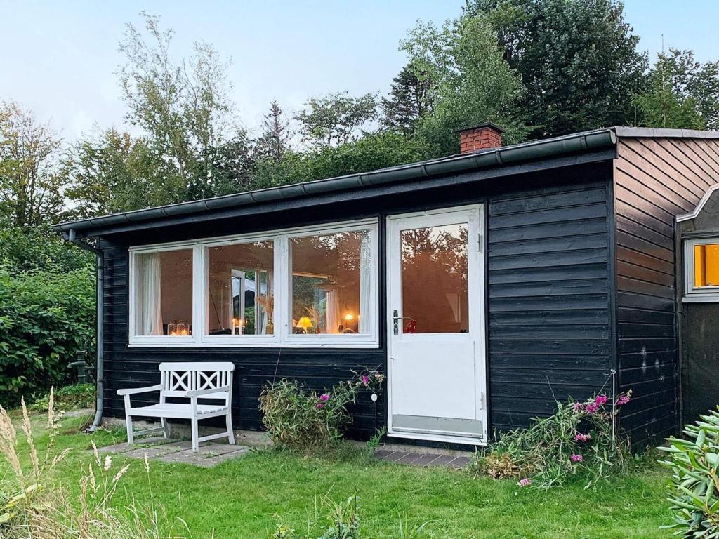 FrederiksværkにあるHoliday home Frederiksværk XXIVの草の中のベンチ付き黒小屋