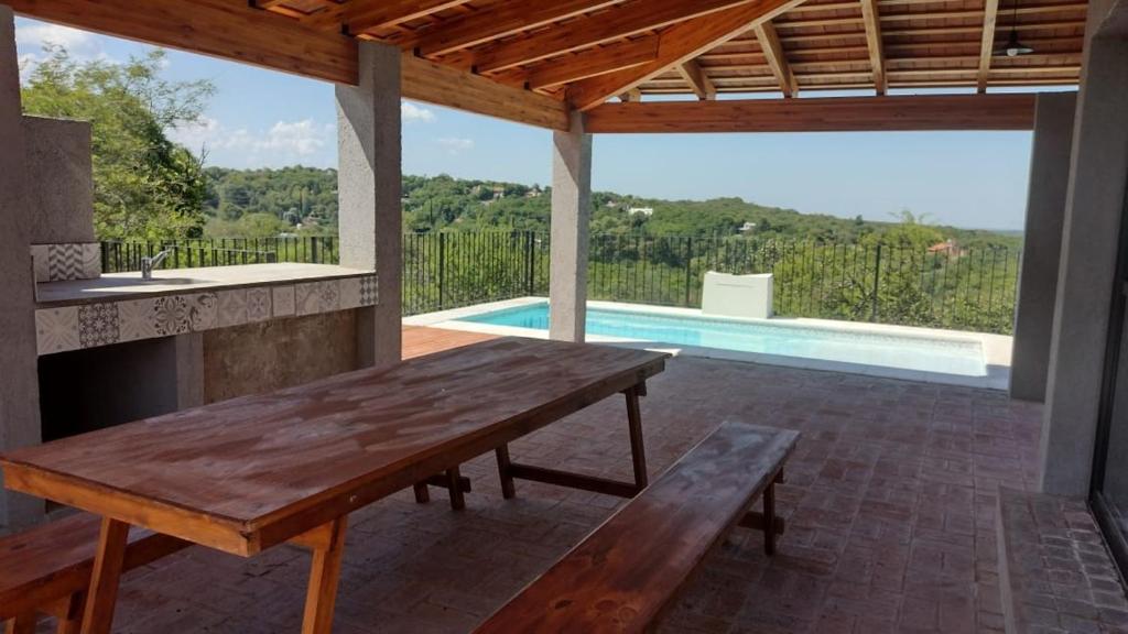 a patio with a wooden table and a swimming pool at La Pasionaria Casa de Campo in Agua de Oro