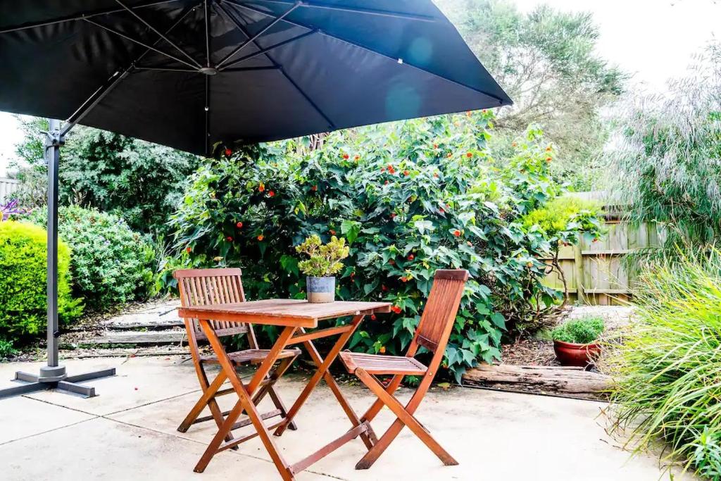 un tavolo in legno e due sedie sotto un ombrellone di Marengo Beach Studios a Marengo