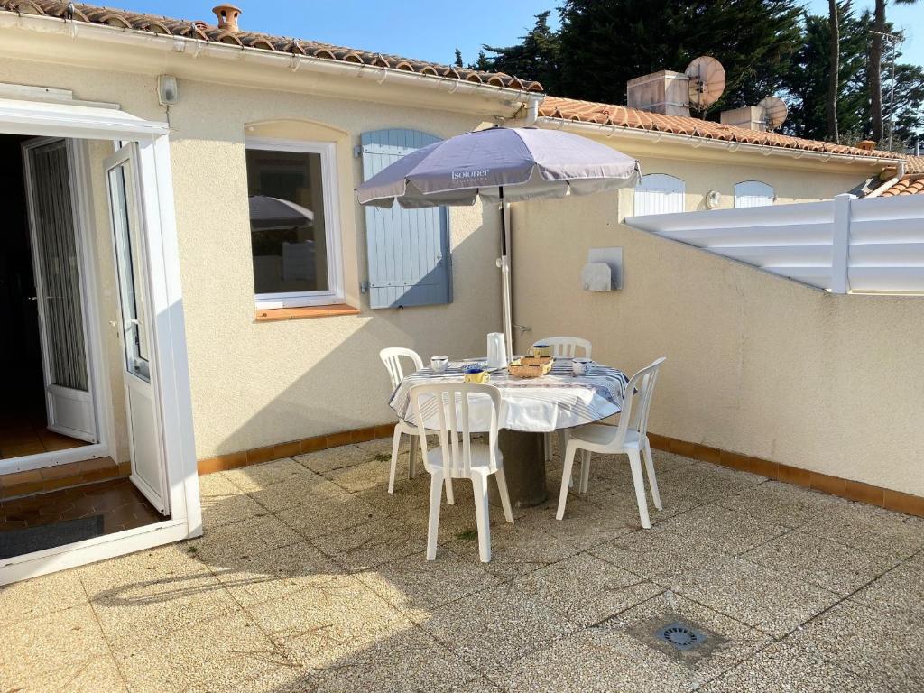 une table et des chaises avec un parasol sur une terrasse dans l'établissement Maison de Vacances Cosy à 800m de la Plage avec Cour Privative et Accès WIFI - FR-1-231-161, à Bretignolles-sur-Mer