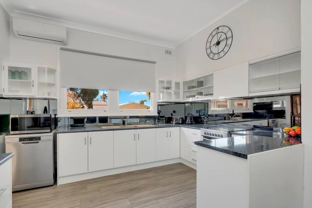 una cocina con armarios blancos y un reloj en la pared en Mabel’s retreat 4 bedrooms,Wifi,Netflix,Kayo, en Broken Hill