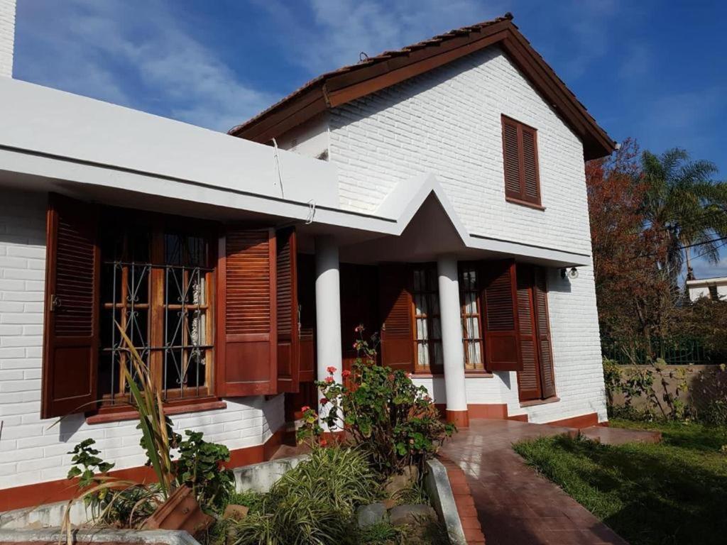 uma casa branca com persianas de madeira e um quintal em Paz y armonía cerca de todo em San Salvador de Jujuy