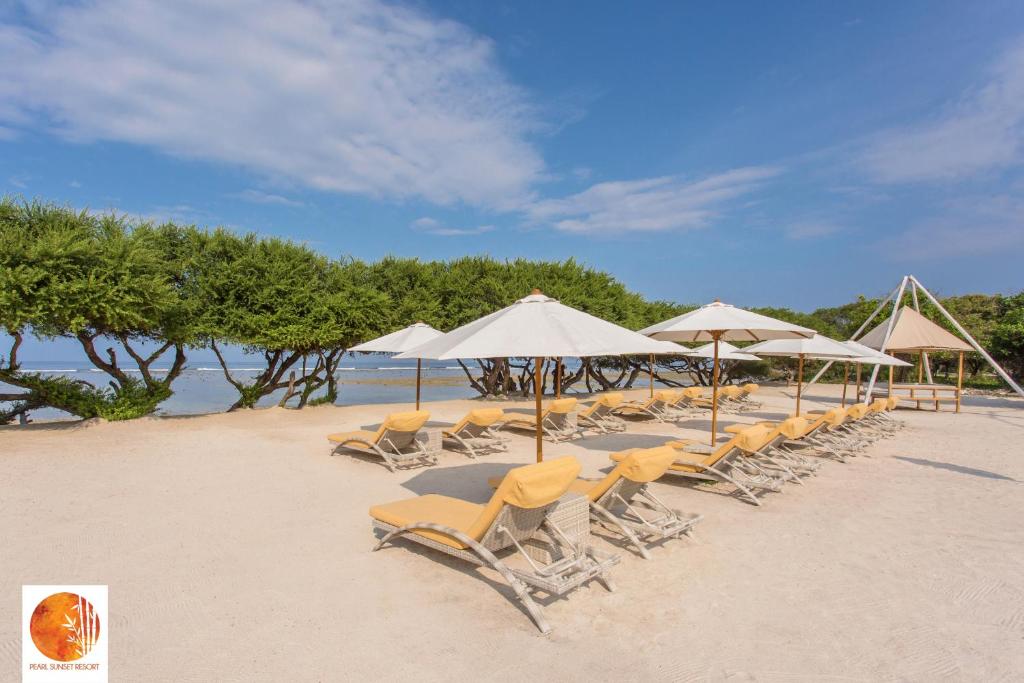 a group of chairs and umbrellas on a beach at Pearl Sunset Resort in Gili Trawangan