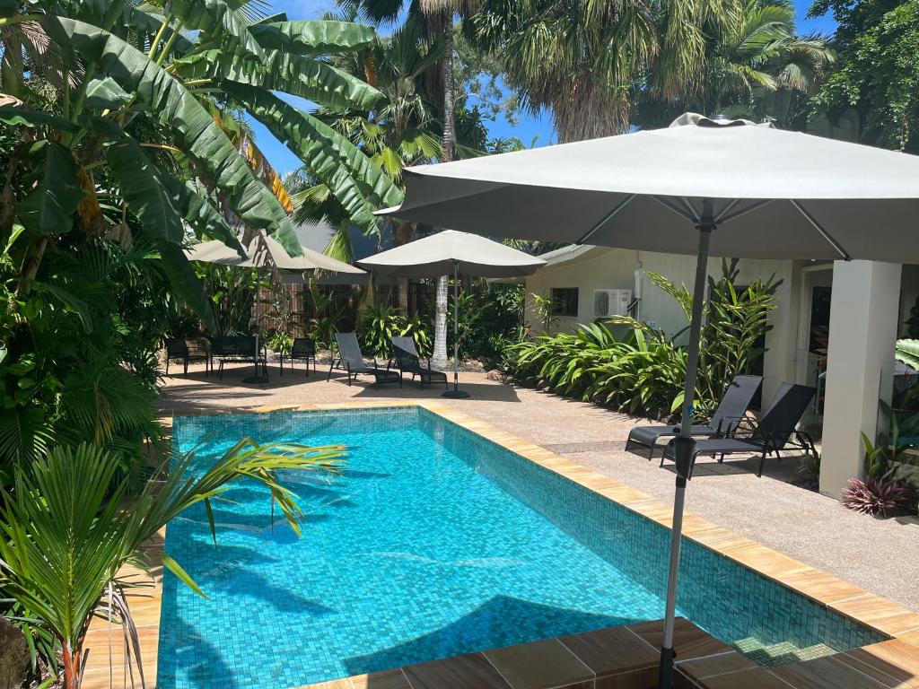 a swimming pool with an umbrella next to a resort at Talpa Tropix- 5 min stroll to beach in Palm Cove
