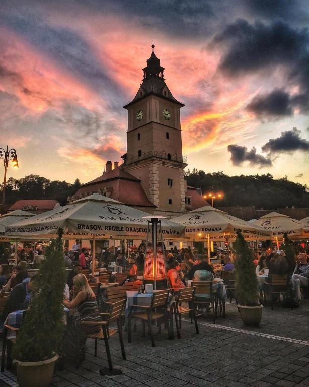 a group of people sitting in chairs in front of a clock tower at Margarets Place in Braşov