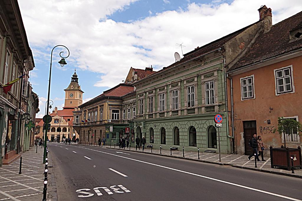 an empty city street with buildings and a clock tower at Celebrity Apartment Brasov in Braşov